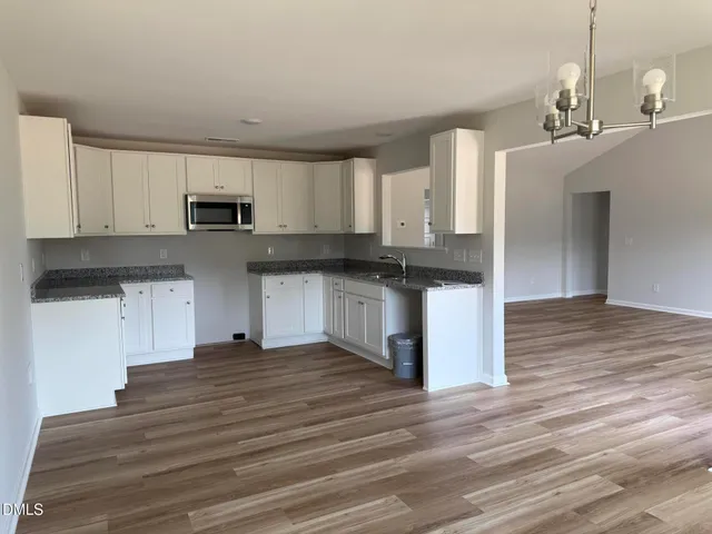 a kitchen with stainless steel appliances granite countertop a stove top oven a sink dishwasher and a refrigerator with wooden floor