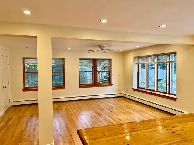a view of an empty room with window and wooden floor