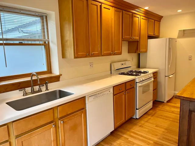 a kitchen with stainless steel appliances granite countertop a refrigerator a sink dishwasher and white cabinets with wooden floor