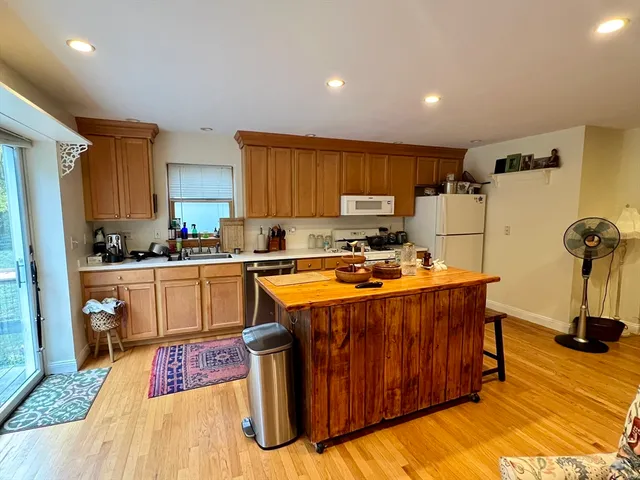 a kitchen with stainless steel appliances granite countertop a stove a sink dishwasher and a refrigerator with wooden floor