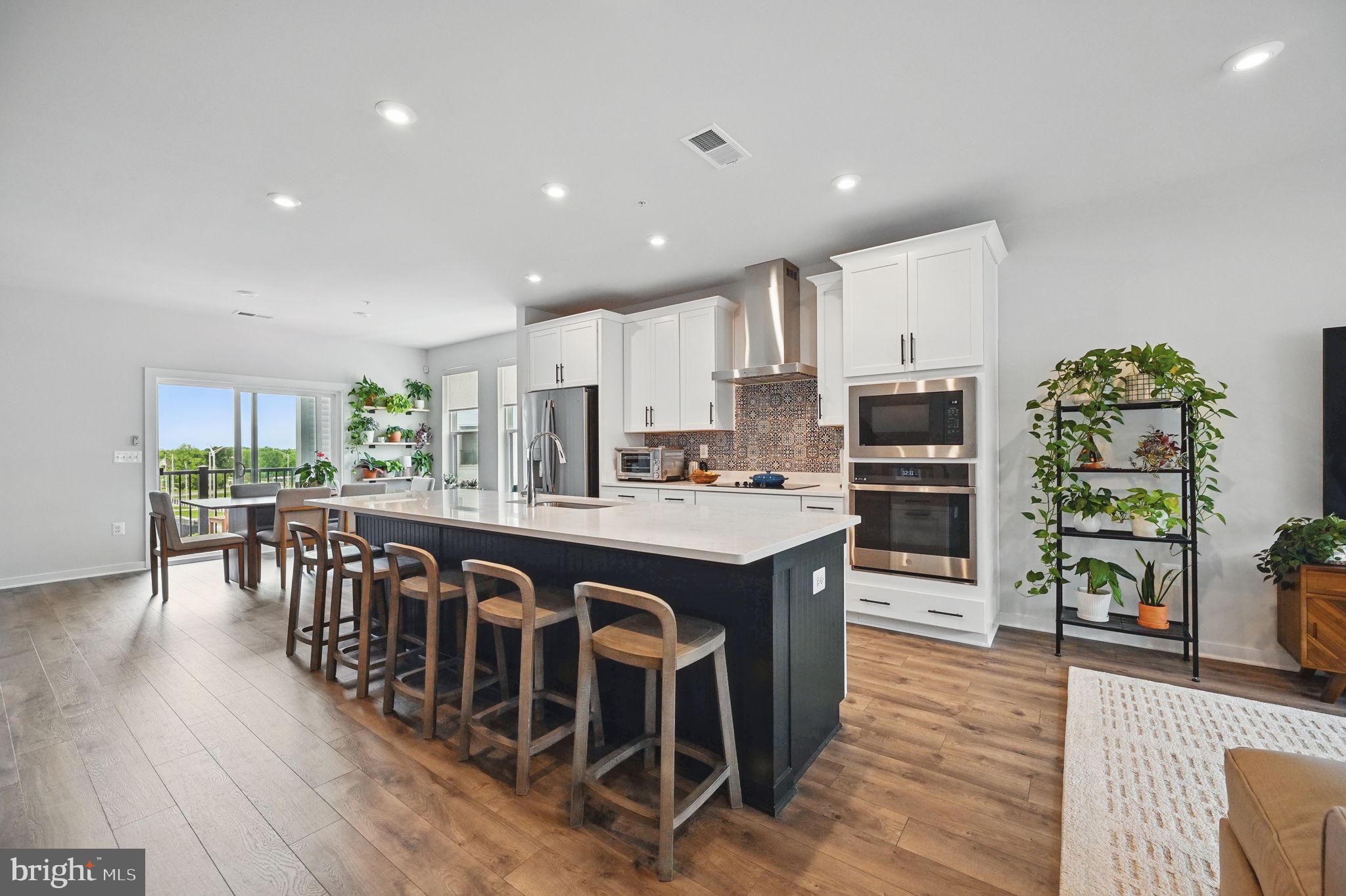 44623 Wolfhound Square Ashburn, VA 20147 - Photo 6 of 29 a large kitchen with stainless steel appliances a dining table chairs and wooden floor