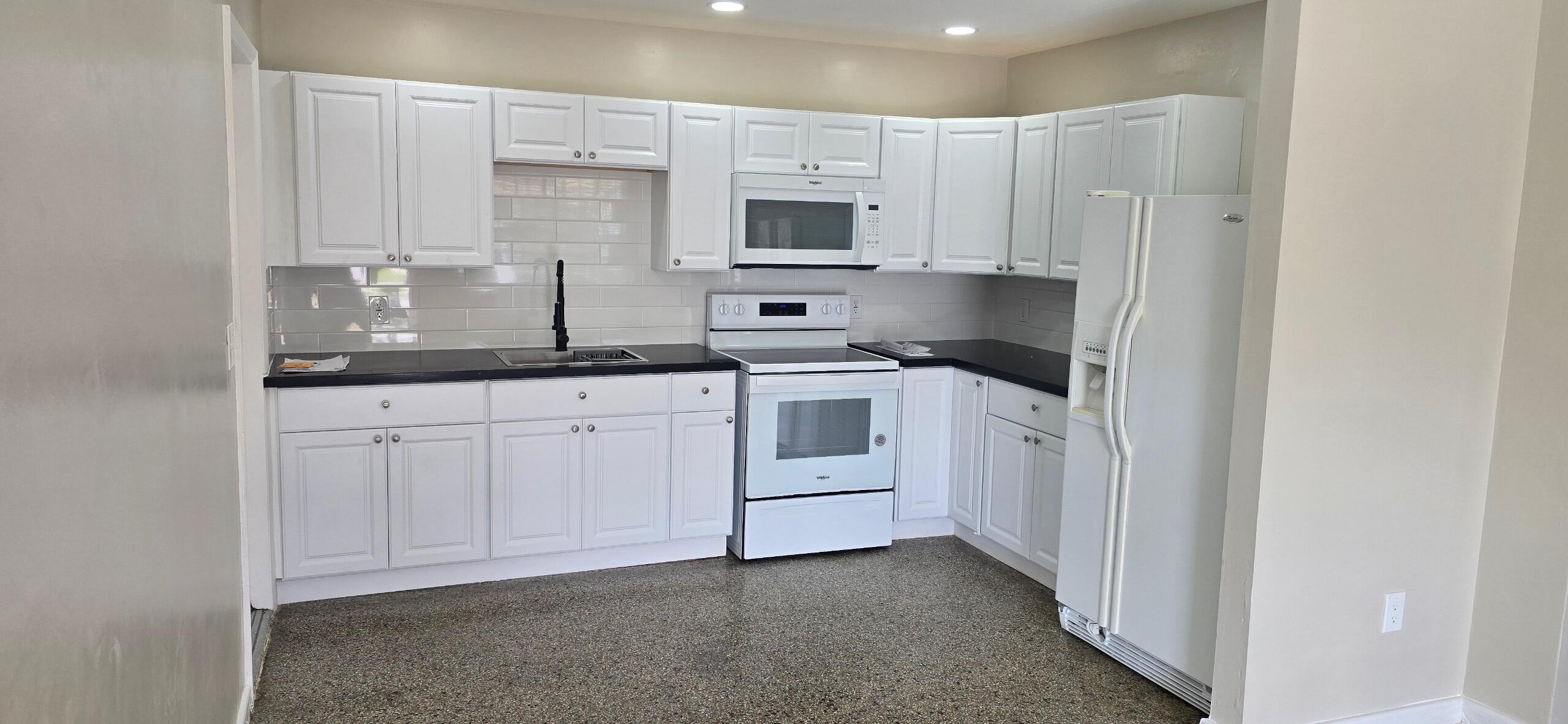 136 West 34th Street, Unit A Riviera Beach, FL 33404 - Photo 3 of 12 a kitchen with white cabinets and stainless steel appliances