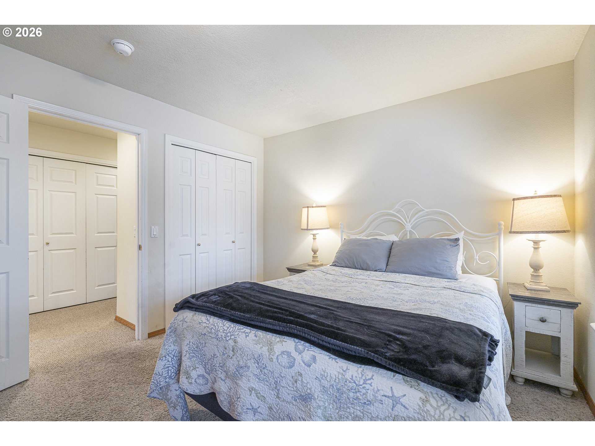 7850 Pine Beach Loop Rockaway Beach, OR 97136 - Photo 15 of 33 a bedroom with a bed a table and a lamp