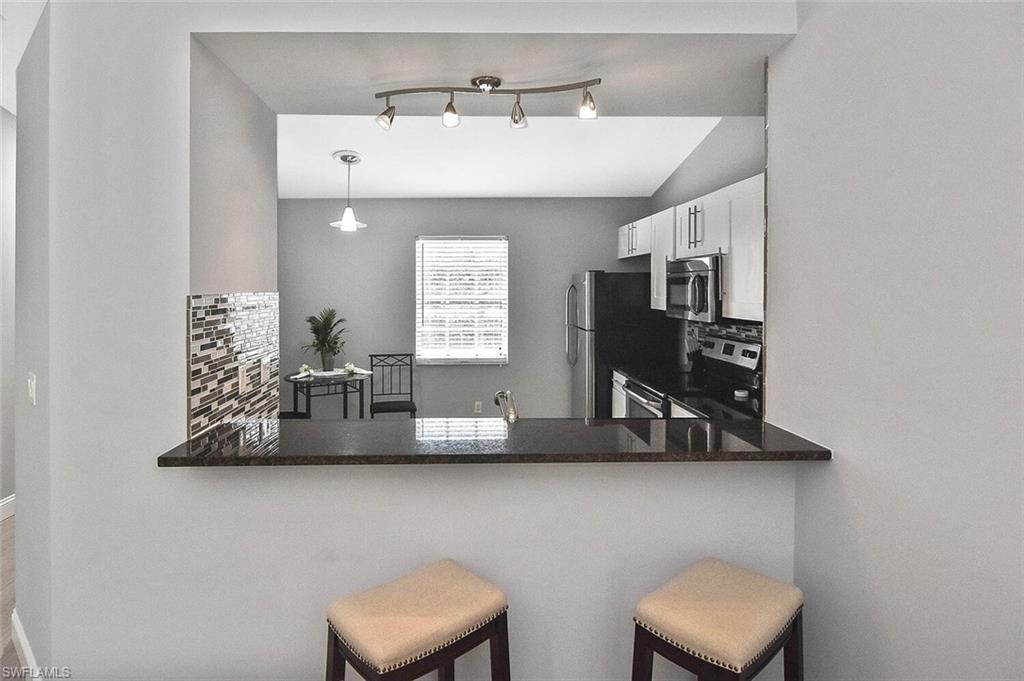 8075 Tiger Cove, Unit 1711 Naples, FL 34113 - Photo 17 of 42 a kitchen with stainless steel appliances a sink a window and a counter top space