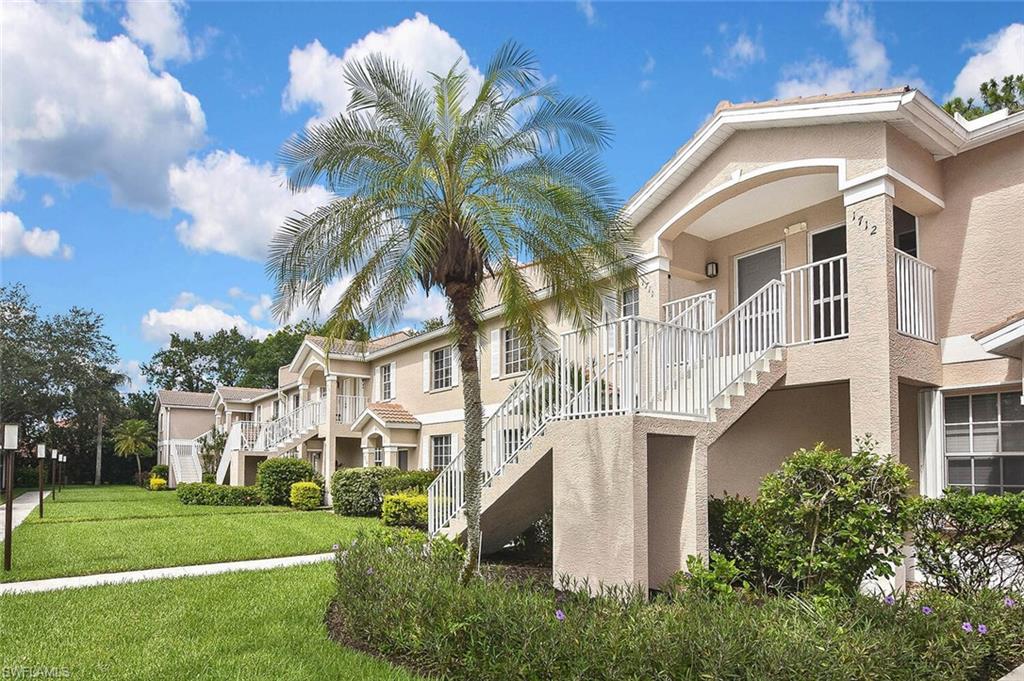 8075 Tiger Cove, Unit 1711 Naples, FL 34113 - Photo 2 of 42 a view of a white building with a big yard and potted plants