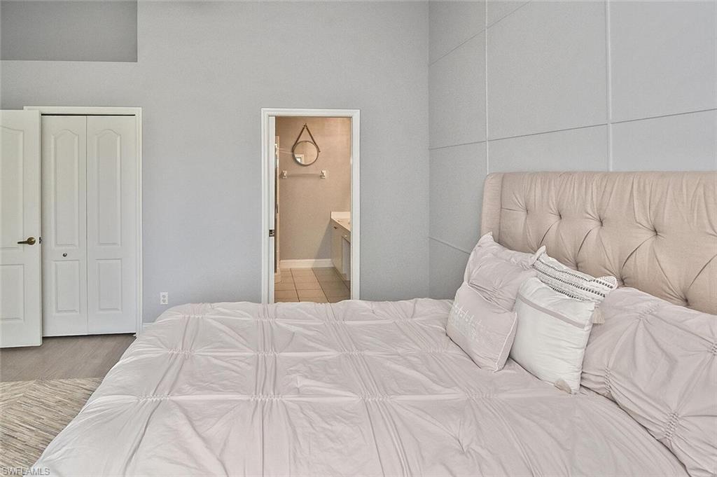 8075 Tiger Cove, Unit 1711 Naples, FL 34113 - Photo 29 of 42 a bedroom with a bed and a night stand
