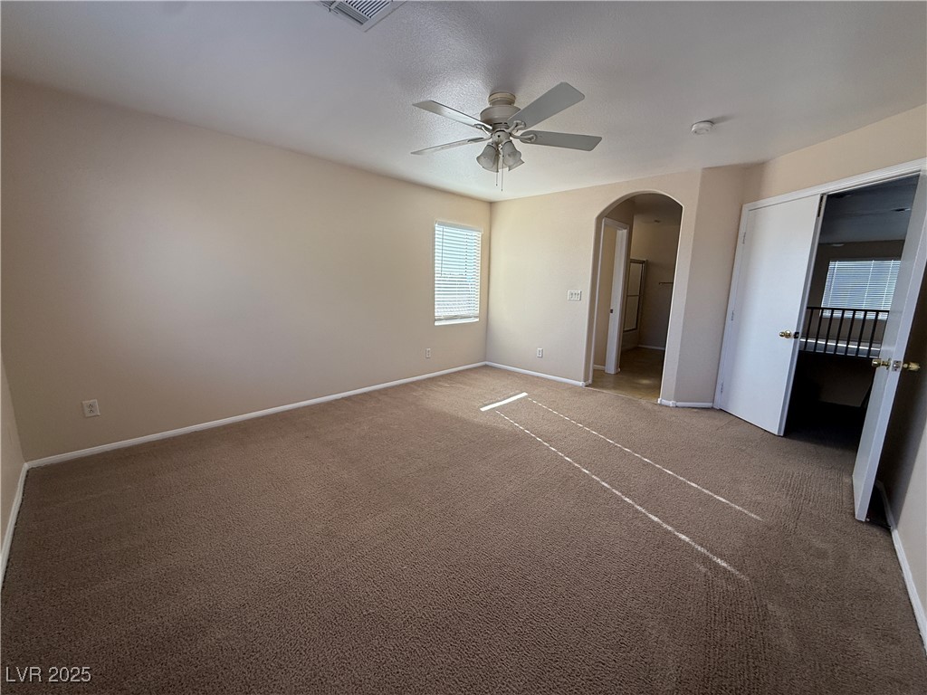 9950 Shadow Grove Avenue Las Vegas, NV 89148 - Photo 20 of 37 Unfurnished bedroom with arched walkways, carpet floors, multiple windows, and a ceiling fan