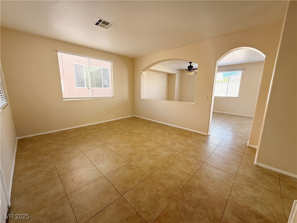9950 Shadow Grove Avenue Las Vegas, NV 89148 - Photo 4 of 37 Empty room featuring arched walkways, a ceiling fan, and light tile patterned flooring