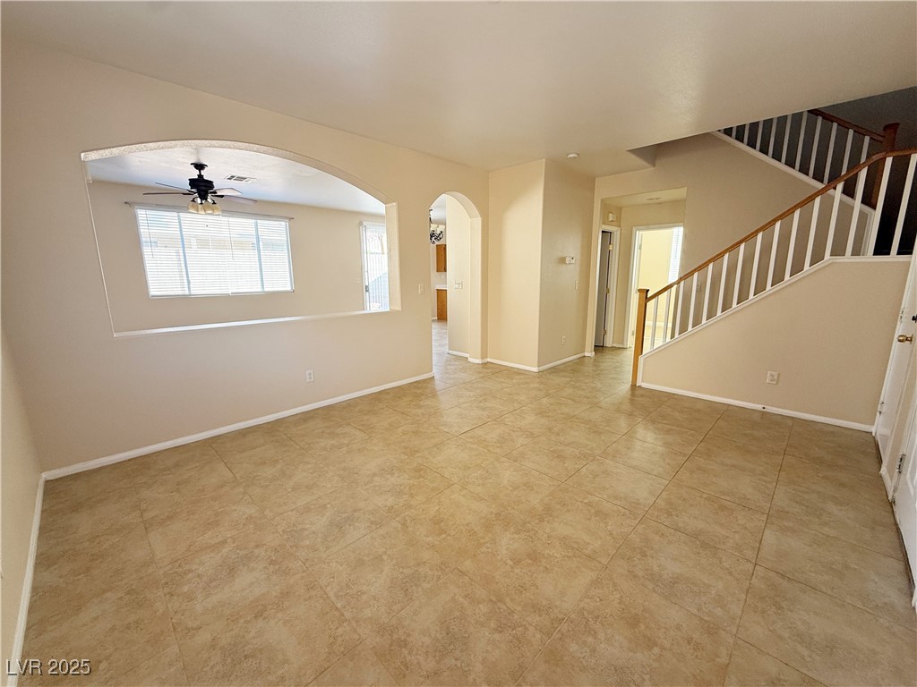 9950 Shadow Grove Avenue Las Vegas, NV 89148 - Photo 5 of 37 Spare room with arched walkways, ceiling fan, stairs, and light tile patterned floors