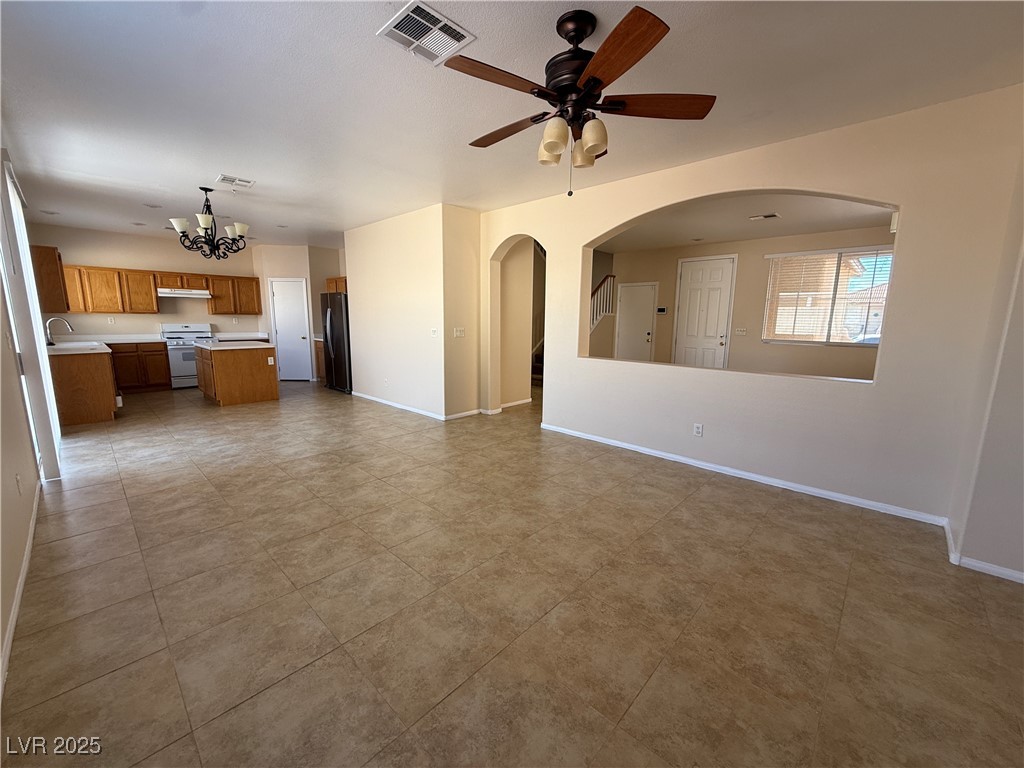 9950 Shadow Grove Avenue Las Vegas, NV 89148 - Photo 8 of 37 Unfurnished living room with a chandelier, ceiling fan, arched walkways, and light tile patterned floors