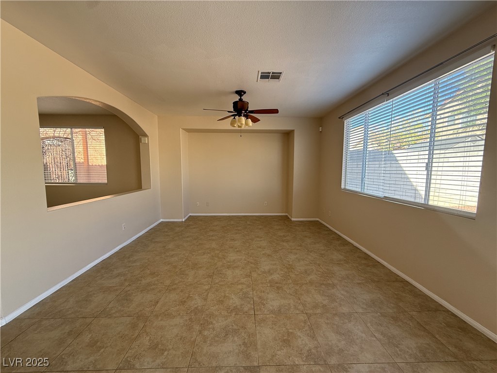 9950 Shadow Grove Avenue Las Vegas, NV 89148 - Photo 9 of 37 Spare room with healthy amount of natural light, a ceiling fan, a textured ceiling, and light tile patterned floors