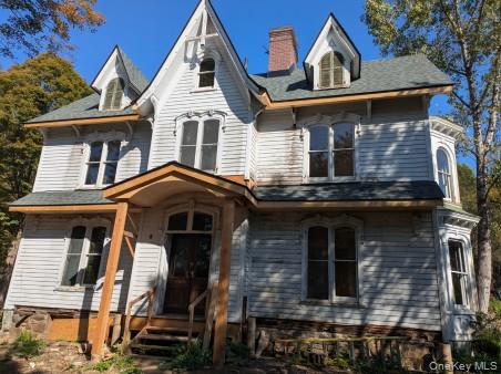 Victorian home featuring covered porch and a chimney