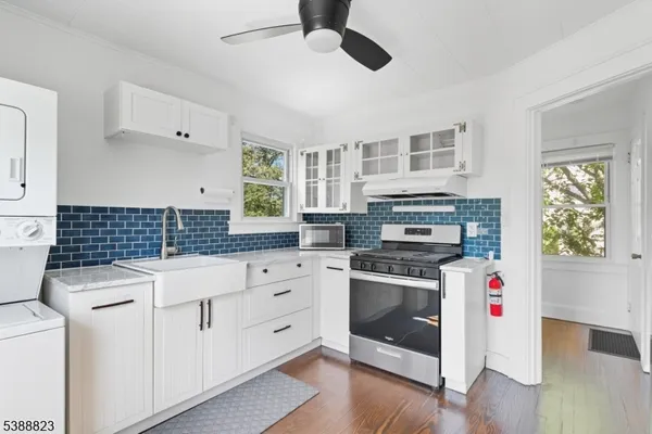 a kitchen with granite countertop a stove a sink and dishwasher with white cabinets
