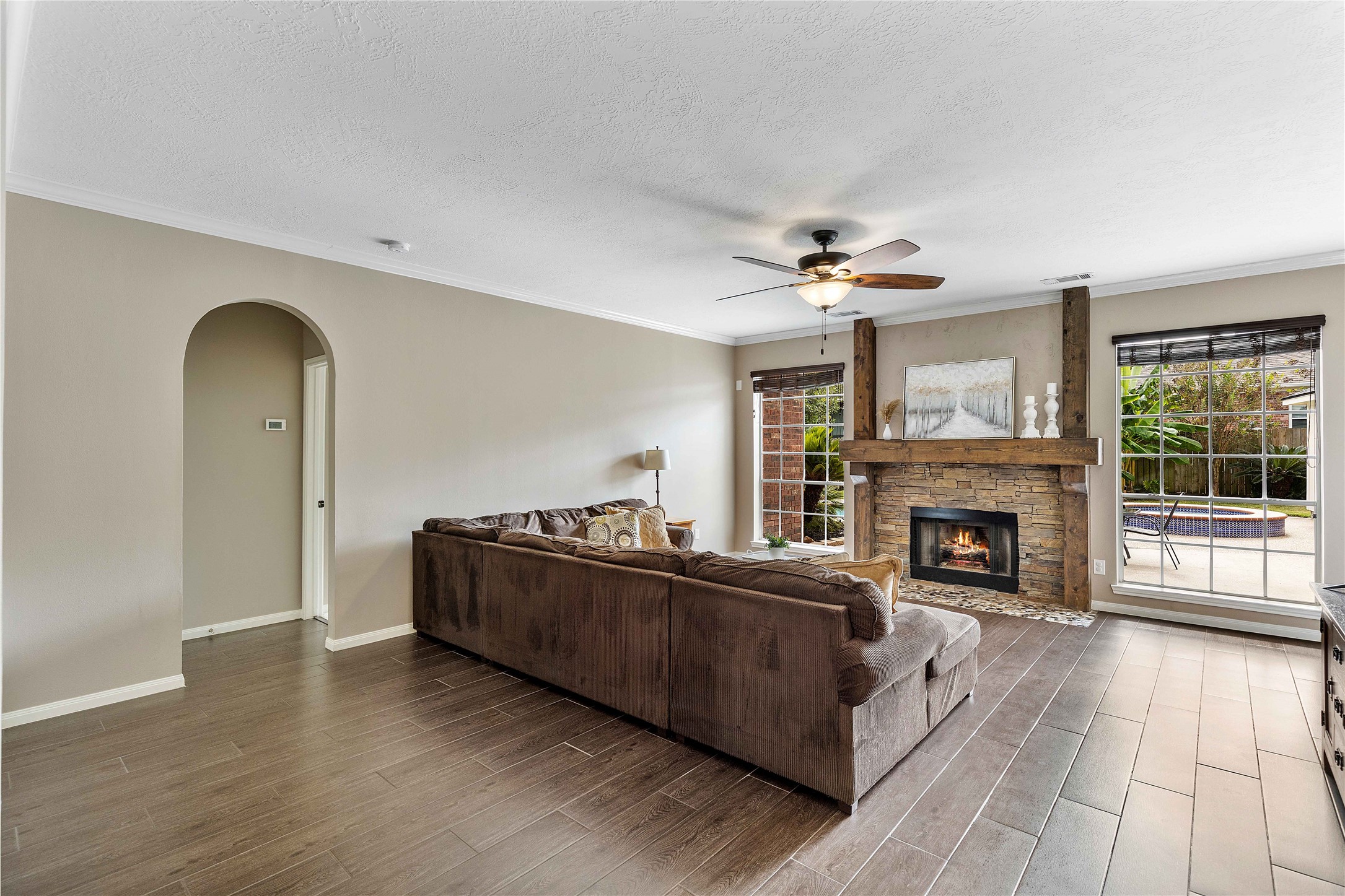 19819 Cherry Oaks Lane Humble, TX 77346 - Photo 14 of 47 This cozy living room features a modern fireplace with a stone and oak surround and large windows providing ample natural light and views of the outdoor pool area. The space is complemented by neutral walls and tile flooring - made to match any furniture pieces you have!