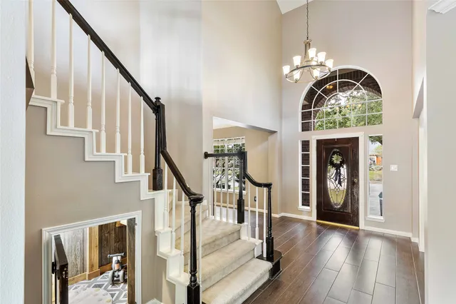 a view of a hallway with wooden floor staircase and livingroom