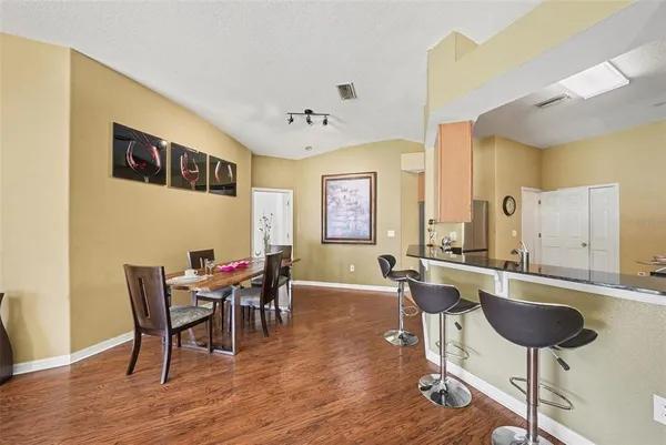 a kitchen with stainless steel appliances granite countertop a stove top oven a sink dishwasher a dining table and chairs with wooden floor