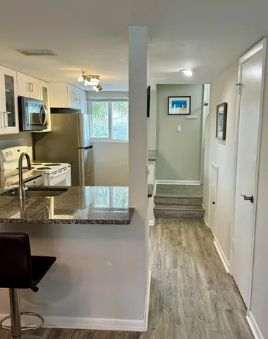 a room with lots of white furniture and a wooden floor