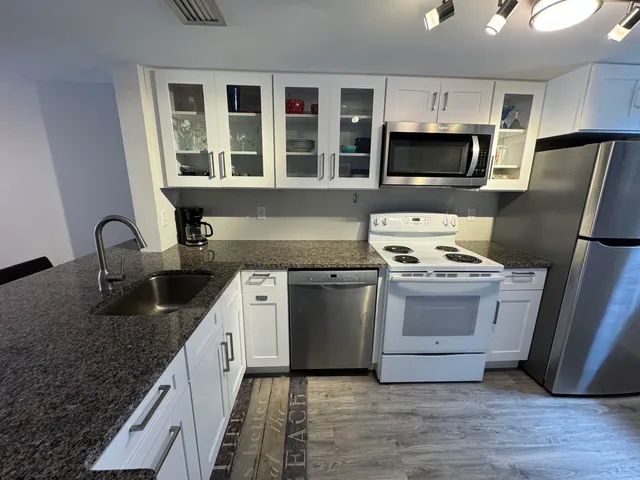 a kitchen with granite countertop a sink and steel appliances
