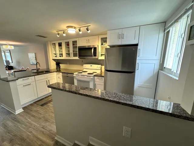 a kitchen with stainless steel appliances granite countertop a refrigerator a sink a stove a microwave and island