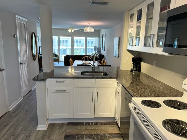 a kitchen with kitchen island granite countertop a sink and a stove with wooden floor
