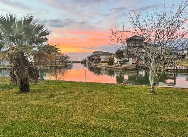 a view of a lake with a yard and large trees