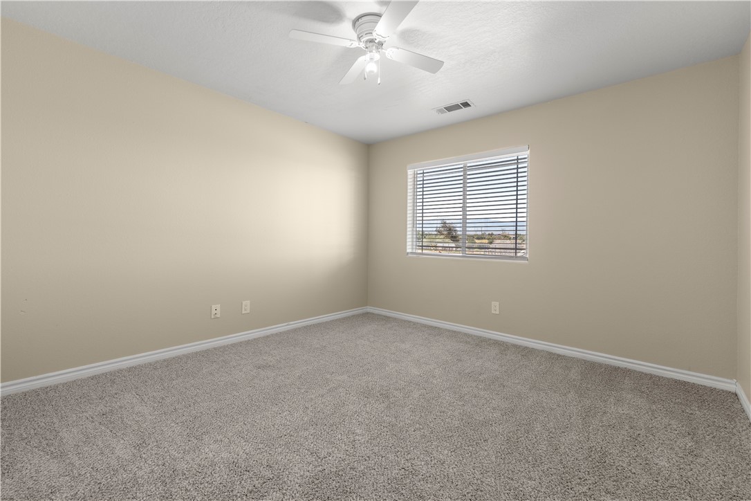8755 Lilac Road Oak Hills, CA 92344 - Photo 11 of 28 an empty room with a window and a fan