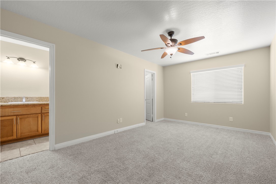 8755 Lilac Road Oak Hills, CA 92344 - Photo 13 of 28 a view of an empty room with a ceiling fan and a window