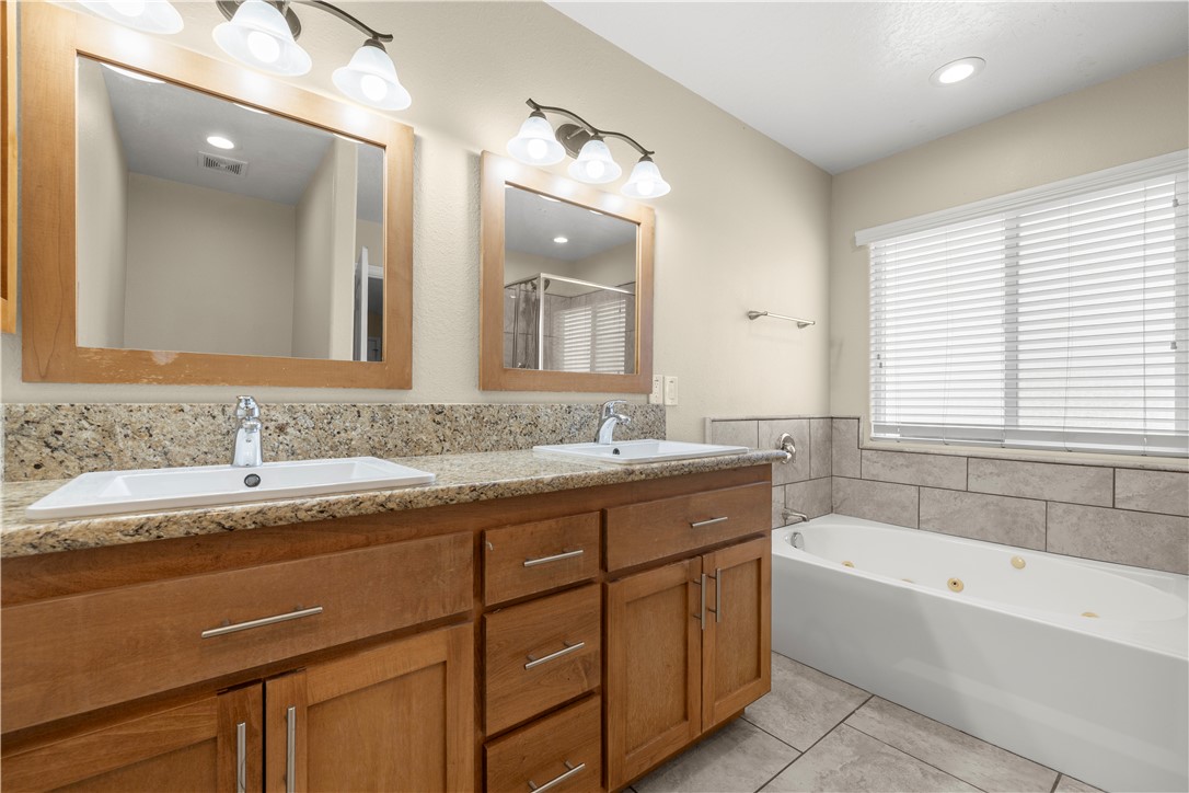 8755 Lilac Road Oak Hills, CA 92344 - Photo 21 of 28 a bathroom with a granite countertop bathtub a double vanity sink and mirror