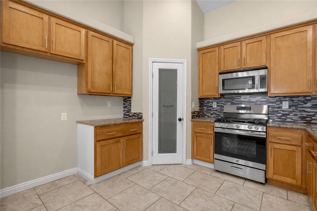 8755 Lilac Road Oak Hills, CA 92344 - Photo 8 of 28 a kitchen with granite countertop a stove top oven microwave and cabinets