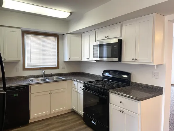 a kitchen with granite countertop a sink cabinets and stainless steel appliances