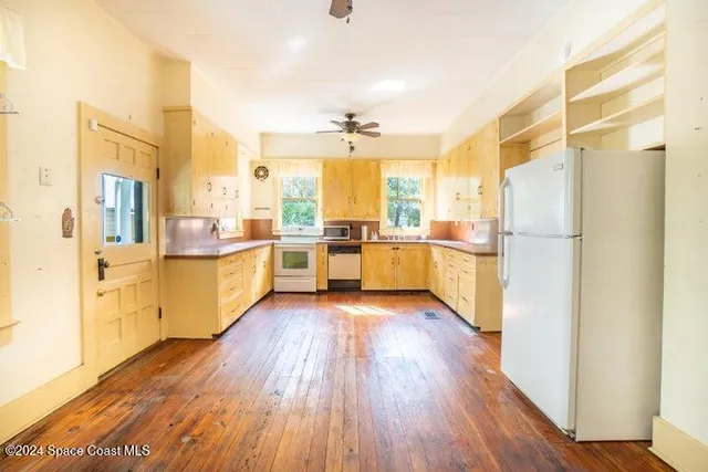 a kitchen with stainless steel appliances a refrigerator a sink dishwasher a stove and white cabinets with wooden floor