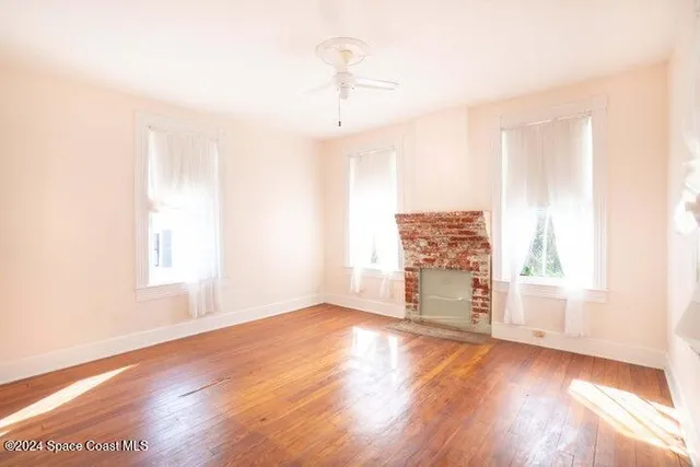 an empty room with wooden floor cabinet and windows