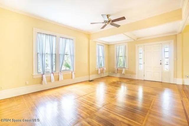 a view of an empty room with a window and wooden floor