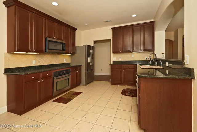 a kitchen with stainless steel appliances granite countertop wooden cabinets a stove top oven a sink and dishwasher