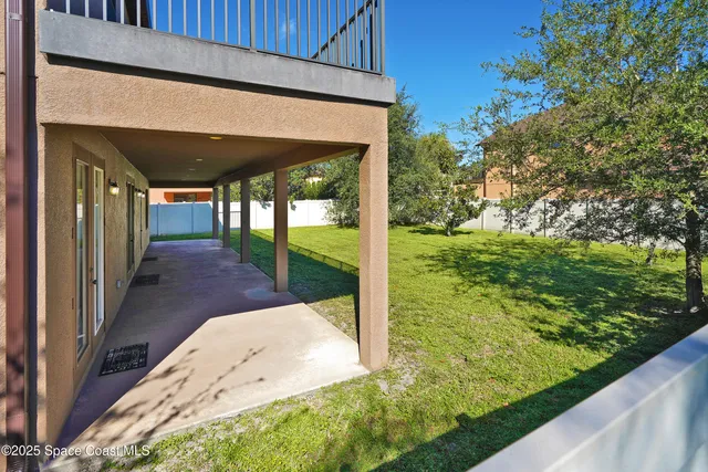a view of a white house with a big yard and potted plants and palm trees
