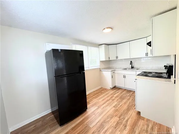a kitchen with a refrigerator a stove and wooden floor
