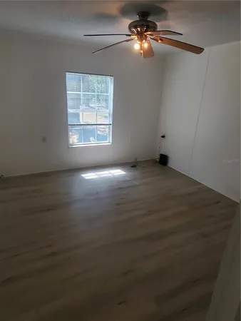 an empty room with windows and fan