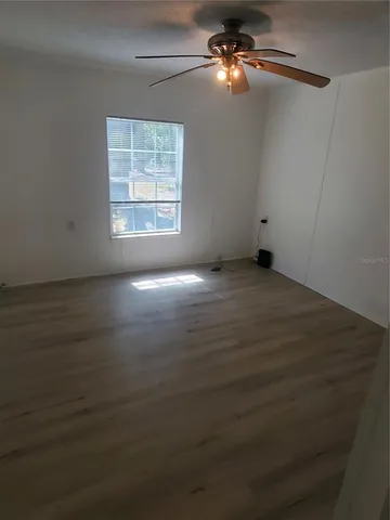 an empty room with windows and fan
