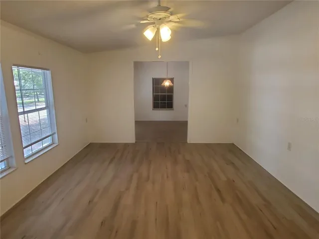 a view of empty room with wooden floor and fan