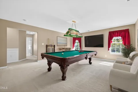 a room with furniture pool table flat screen tv and windows