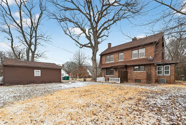 a front view of a house with a yard covered with snow