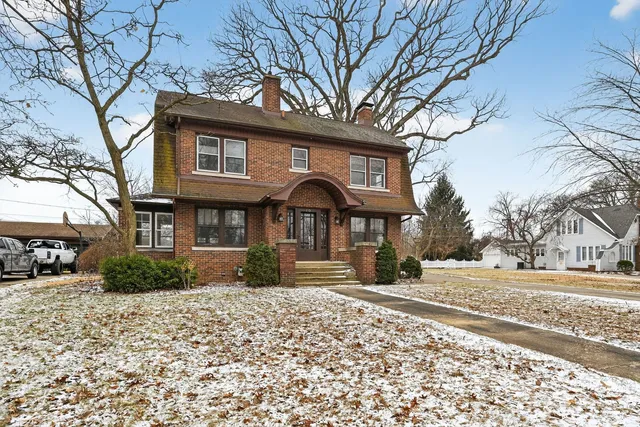 a front view of a house with a yard covered in snow