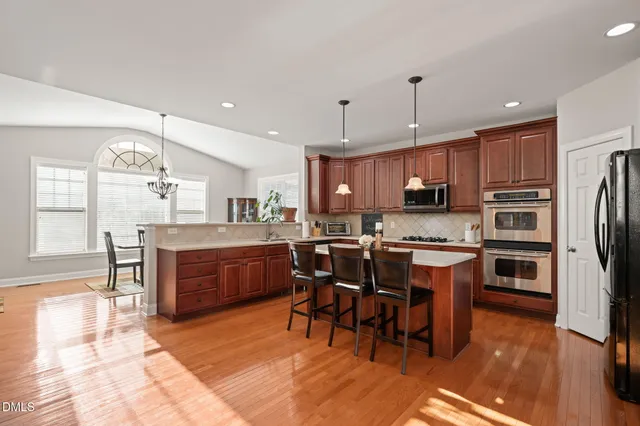 a kitchen with stainless steel appliances granite countertop a sink a stove and a wooden floors