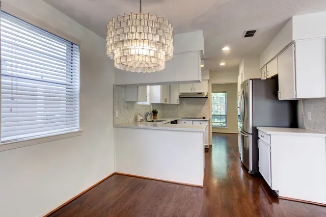 a kitchen with stainless steel appliances granite countertop a refrigerator a sink dishwasher a stove and a dining table with wooden floor