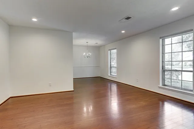 an empty room with wooden floor and windows with curtains