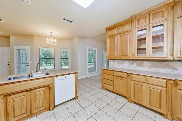 a large kitchen with kitchen island granite countertop a refrigerator a sink dishwasher a dining table and chairs with wooden floor