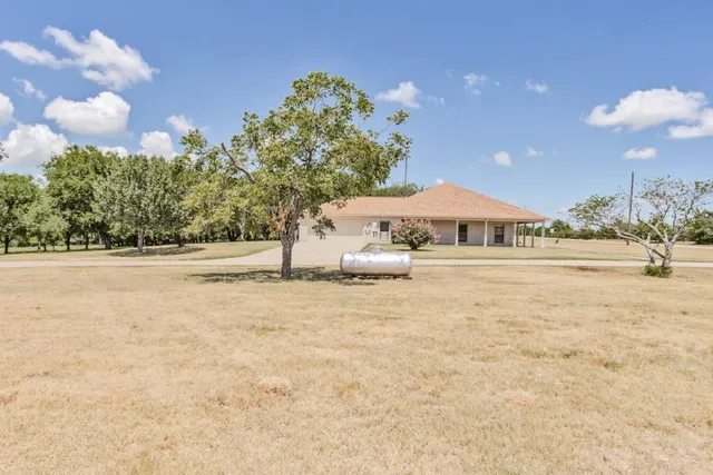 a front view of a house with a yard and large trees