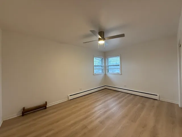 an empty room with wooden floor fan and windows