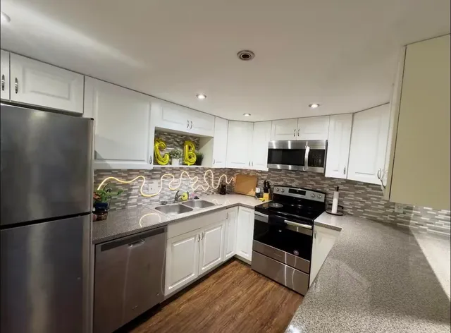 a kitchen with stainless steel appliances granite countertop a refrigerator a stove a sink and a microwave