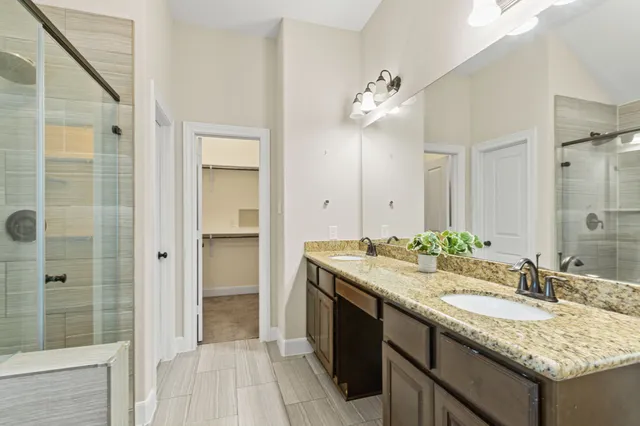 a bathroom with a granite countertop sink a mirror and a shower